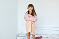 Portrait of small girl wearing large striped shirt and beige short pretending to be a grown up woman. Girl child posing in