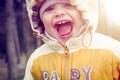 Portrait of small happy child in hood and warm clothes in early spring. Laughing baby in nature