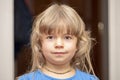 Portrait of a small laughing blonde girl on a dark background, close-up, selective focus.