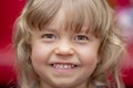 Portrait of a small laughing girl with blonde hair in a room on a colored blurred background, close-up, selective focus.