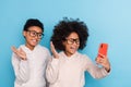 Portrait of small little friends friendship trendy cheery kids taking selfie waving hi  over bright blue color Royalty Free Stock Photo