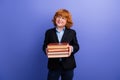 Portrait of small positive minded person hands hold pile stack book look interested empty space isolated on purple color Royalty Free Stock Photo