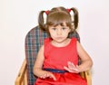 Portrait of a small three-year-old girl sitting on a children`s chair on a bright background