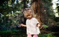 Portrait of small toddler girl outdoors in summer nature, holding strawberries.