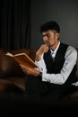 Smart attractive adult asian businessman sitting on sofa, reading a book in the office Royalty Free Stock Photo