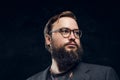 Portrait of a smart bearded man in glasses in a dark studio