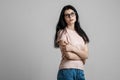 Portrait of smart beautiful brunette girl in eyeglasses with natural make-up, on grey background. Royalty Free Stock Photo