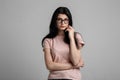 Portrait of smart beautiful brunette girl in eyeglasses with natural make-up, on grey background. Royalty Free Stock Photo