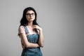 Portrait of smart beautiful brunette girl in eyeglasses with natural make-up, on grey background. Royalty Free Stock Photo