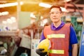 Portrait of smart engineer Asian Chinese happy labor worker handsome model in heavy industry background.Hard hat off hand holding