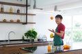 Portrait smart and handsome Asian man preparing healthy meal and drinking fresh organic orange juice in the loft style kitchen Royalty Free Stock Photo