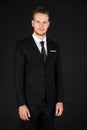 Portrait of young smart and handsome business man in black suit standing on isolated black background Royalty Free Stock Photo