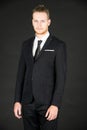 Portrait of young smart and handsome business man in black suit standing on isolated black background Royalty Free Stock Photo