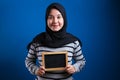 Portrait of smart happy successful Asian muslim woman wearing hijab smiling at camera while holding empty chalkboard Royalty Free Stock Photo