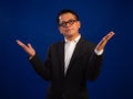 Portrait of smart middle-aged asian confident successful businessman wearing suit with welcoming gesture on blue background Royalty Free Stock Photo