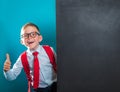 Portrait of smart school child with thumb up near blackboard blank and looking at camera. Happy kid boy in uniform. Go Royalty Free Stock Photo