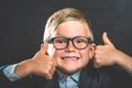 Portrait of smart school child with thumb up near blackboard blank and looking at camera. Happy kid boy in uniform. Go Royalty Free Stock Photo