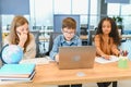 Portrait of smart schoolgirls and schoolboys looking at the laptop in classroom Royalty Free Stock Photo