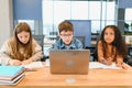 Portrait of smart schoolgirls and schoolboys looking at the laptop in classroom Royalty Free Stock Photo