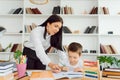 Portrait of smart tutor with pencil correcting mistakes in pupil?s notebook