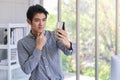 Portrait of smart young asian businessman using smart mobile phone to take a selfie picture in the office room Royalty Free Stock Photo