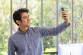 Portrait of smart young asian businessman using smart mobile phone to take a selfie picture in the office room Royalty Free Stock Photo