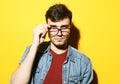 Portrait of a smart young man wearing eyeglasses standing against yellow background Royalty Free Stock Photo