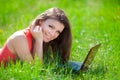 Portrait of a smart young woman lying on grass and using laptop Royalty Free Stock Photo