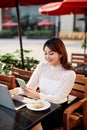 Portrait of smart young woman with mobile phone working on laptop at outdoor coffee shop Royalty Free Stock Photo