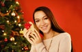 Portrait, smile and Christmas with woman, gift box and package on a red studio background. Face, person and girl with Royalty Free Stock Photo