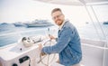 Portrait smile happy man driver captain of white luxury yacht holding helm wheel, summer travel on boat sea Royalty Free Stock Photo