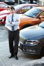 Portrait, smile and a man arms crossed in a parking lot for car sale at a commercial dealership. Business, luxury and