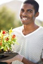 Portrait, smile and planting flowers with black man in garden of home for summer landscaping. Face, nature and gardening Royalty Free Stock Photo