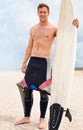 Portrait, smile and shirtless man with surfboard on beach in wetsuit for sports, travel or fitness. Nature, sky and body Royalty Free Stock Photo