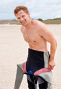 Portrait, smile and surfer man in wetsuit at beach for sports, fitness or exercise on summer vacation. Travel, health Royalty Free Stock Photo