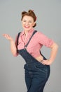 Portrait of smiled and cheerful pin-up woman standing with arm on hips and holding copy space on her palm Royalty Free Stock Photo