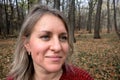 Portrait of smiled mature woman in autumn forest. Girl does not look at camera on blurred background. Thought, meditation or doubt Royalty Free Stock Photo