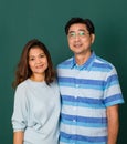 Portrait of a smiley happy loving Asian couple dressed casually standing relaxedly, smiling to a camera for studio shot over green Royalty Free Stock Photo