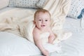 Portrait of smiling adorable baby boy covered in big blanket lying on bed Royalty Free Stock Photo