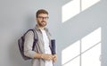 Portrait of a smiling adult male student with backpack and folders over grey wall background. Royalty Free Stock Photo