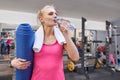 Portrait of smiling adult woman with bottle of water and sports mat in health club. Health fitness sport concept Royalty Free Stock Photo