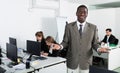 Portrait of smiling African American businessman welcoming to busy modern coworking space