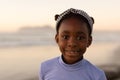 Portrait of smiling african american cute girl wearing headband against sea and clear sky at sunset Royalty Free Stock Photo