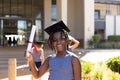 Portrait of smiling african american elementary schoolboy wearing mortarboard showing degree