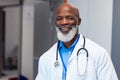 Portrait of smiling african american senior male doctor in hospital corridor Royalty Free Stock Photo