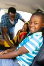 Portrait of smiling african american siblings with father teaching to wear seat belt in car Royalty Free Stock Photo