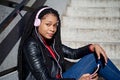 Portrait of a smiling African-American woman with a cell phone is chatting or listening to music on the streets of the city. The Royalty Free Stock Photo