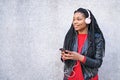 Portrait of a smiling African-American woman with a cell phone is chatting or listening to music on the streets of the city. The Royalty Free Stock Photo