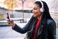 Portrait of a smiling African-American woman with a cell phone is chatting or listening to music on the streets of the city. The Royalty Free Stock Photo