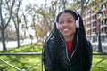 Portrait of a smiling African-American woman with a cell phone is chatting or listening to music on the streets of the city. The Royalty Free Stock Photo